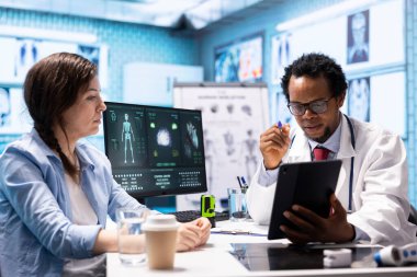 Doktor, kabinedeki kadın hastaya sağlık sigortası ve sağlık hizmetleri hakkında teşhis raporunu açıklıyor. Afrikalı Amerikalı doktor müşterilerine profesyonel danışmanlık ve geri bildirim yapıyor.