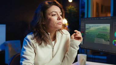 Ham görüntüleri parlatan, kurgu tekniklerini uygulayan netlik, keskinlik ve parlaklığı arttıran video editörü. Videograf ofiste kahve içerken klipleri ayarlıyor, kamera B