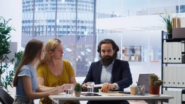 Finansal danışman müşterilerle gelir yönetimi bütçesinin önemi hakkında görüşüyor ve onlara yazılı rehberlik sunuyor. Anne ve kızı para biriktirmek için en iyi uygulamaları keşfettiler, kamera B