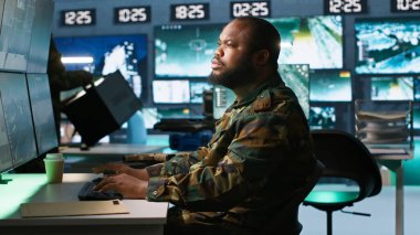 Komuta merkezindeki subay, meslektaşı tarafından düşman birlikleri hakkında bilgi toplamak, analiz etmek ve planlamak için yardım edildi. Operasyon üssündeki ajanlar düşman zayıf noktalarını, kamera A 'yı değerlendiriyor.