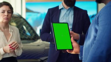 Satış elemanı müşterilerine yeşil ekran tabletinde araba modellerini gösteriyor, tavsiyelerde bulunuyor. Showroom temsilcisi Chroma Key cihazındaki müşterilere finansman seçenekleri sunar, Kamera A