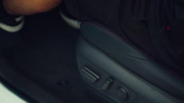 Arabanın şoför koltuğunu düğmelerle ayarlayan adama yaklaş. Sürücünün rahatlığı için yükseltilebilen, alçaltılabilen, eğrilebilen, ileri ve geri hareket edebilen bir araç sandalyesi.