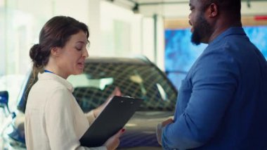 Satış temsilcisi müşteriyle konuşuyor, tercihlerini, ilgi alanlarını ve vücut dillerini gözlemliyor ve onların satın alma kararlarını neyin etkileyebileceğini kavrayabilmek için not alıyor.