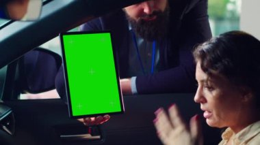 Araba satıcısı, test sürüşünü bitirdikten sonra müşterilerine izole edilmiş ekran tabletinin son fiyatını gösteriyor. Otomobil kataloğunu Chroma Key Cihazı 'ndaki müşterilere gösteren satış temsilcisi, kamera A