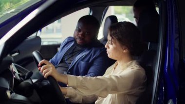 Deneme sürüşü sırasında araçtaki sorunları gözlemledikten sonra galeri satıcısıyla tartışan bir adam. Kocasının yanındaki direksiyondaki üzgün kadın, araba kullandıktan sonra fark edilen endişeleri anlatıyor, kamera B