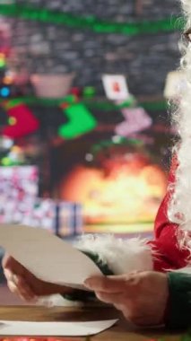 Dikey Video Aziz Nick yazışmalarını kontrol ediyor ve Noel arifesi yolculuğuna zamanında mektupları okuyor, çocuklar için hediyeler hazırlıyor. Kırmızı elbisesiyle beyaz sakallı Noel Baba. Kamera A.