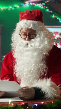 Noel Baba 'nın dikey videosu Kuzey Kutbu kütük kulübesindeki çocukların dilek listesini okuyor. Rüyaların ve oyuncakların kartpostalları geleneksel Noel atölyesinde tatil ruhunu ısıtıyor. Kamera B.