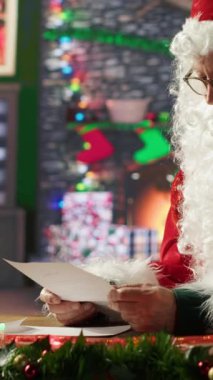 Noel Baba 'nın dikey videosu Kuzey Kutbu kütük kulübesindeki çocukların dilek listesini okuyor. Rüyaların ve oyuncakların kartpostalları geleneksel Noel atölyesinde tatil ruhunu ısıtıyor. Kamera A.