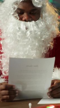 Dikey Video Aziz Nick, Kuzey Kutbu 'ndaki rahat kulübesinde Noel mektupları okuyor. Etrafı şenlikli süslemeler ve parıldayan ışıklarla çevrili. Gelenek ve sihir bayram neşesini canlandırır