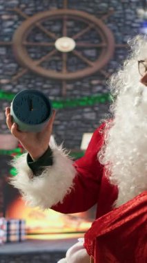 Aziz Nicholas 'ın Noel arifesini vurgulayan dikey videosu şenlik kabininde bir duvar saatiyle büyülü neşe ve tatil ruhunu hissederek. Noel Baba Kuzey Kutbu 'nda Noel kutlaması yapıyor.