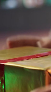 Dikey Video Aziz Nicholas, kır evindeki kurdele ve fiyonklarla birçok hediyeyi süslüyor. Kırmızı elbiseli Noel Baba, Kuzey Kutbu 'nda Noel hediyeleri için renkli ambalaj kağıdı kullanıyor.