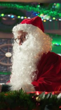 Dikey Noel Baba hediye takibi için internet sayfalarında gezinen şenlikli kütük kulübesinde dizüstü bilgisayar kullanıyor. Kuzey Kutbu Noel büyüsüyle dolu. Aziz Nicholas dijital çağı kucaklıyor.