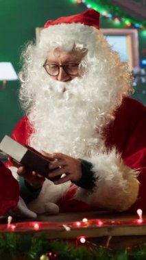 Aziz Nicholas 'ın Noel arifesini vurgulayan dikey videosu şenlik kabininde bir duvar saatiyle büyülü neşe ve tatil ruhunu hissederek. Noel Baba Kuzey Kutbu 'nda Noel kutlaması yapıyor.