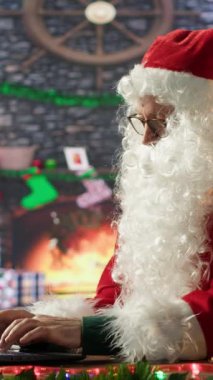 Dikey Video Aziz Nicholas, Kuzey Kutbu 'ndaki şenlikli kulübesinde Noel web sitelerine bakmakla meşgul. Noel Baba internet sitelerinde hazırlık yapıyor, büyülü kış tatili sezonunu yayıyor.