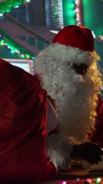 Dikey Kara Klip Aziz Nick, Kuzey Kutbu atölyesindeki ateşin yanında bir hediye kutusu, tatil süslemeleri ve hediye verme büyüsü hazırlıyor. Noel Baba Noel arifesinde çocuklara hediye paketleri hazırlar. Kamera B.