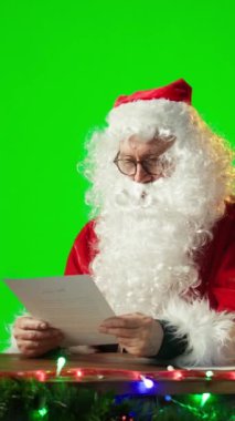 Dikey Video Noel Baba izole edilmiş bir kopya ekran karşısında oturuyor ve dünyanın dört bir yanındaki çocuklardan gelen mektupları okuyor. Yaşlı Aziz Nick Noel tatili için şenlik ruhunu yayıyor. Kamera.