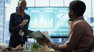 Kaynakları tahsis etmek için birlikte çalışan çeşitli meslektaşlar grubu, etkileşimli kuruldaki bilgi ve satış rakamlarını gözden geçirmek için toplantı odasında bir toplantıya katılıyor. Proje yönetimi. Kamera A.