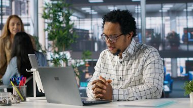 Siyahi adam genel müdürü ekibiyle video bağlantısı kurar, iş operasyonlarını ve stratejik hedefleri gözden geçirir. Verimli karar verebilmek için çevrimiçi iletişimi kullanmak. Kamera A.