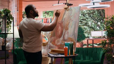 Erkek sanatçı, sanat galerisi sergisi için yaratıcı süreci boyunca belli bir resim tekniği kullanarak yeni başyapıtı üzerinde çalışıyor. Tuval üzerinde güzel bir eser. Kamera B.