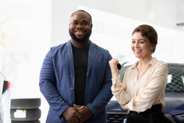 Araba galerisinde araba anahtarlarını tutarak yatırım yapmaya karar verdikten sonra kutlama yapan mutlu karı koca. Galerideki mest olmuş kadın ve erkek araç satışından sonra mutlu hissediyorlar.