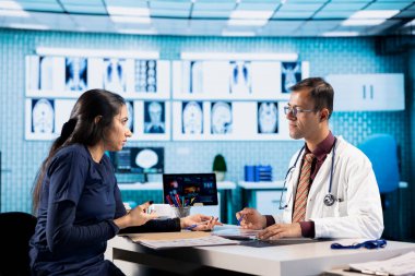 Bir hastanın teşhis raporlarını ve test sonuçlarını inceleyen tıbbi personel röntgen görüntüleme ve tarama yorumlarına odaklanıyor. Klinikteki radyografi faturalarını incelemek için modern danışma.