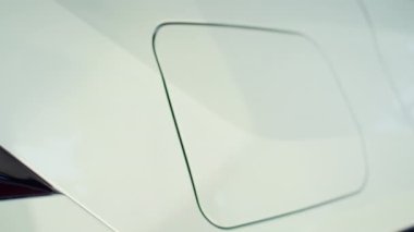 Otomobilin dış kaplamasını yakın çekim. Şarj kapağı insan tarafından tekrar şarj edilecek. İskele kapağının kilidini açmaya odaklan, araç ikmali için hazırlanıyor.