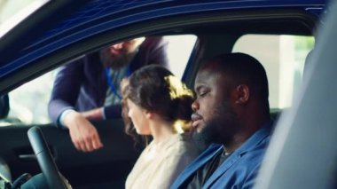 Müşteriler araba almadan önce test sürüşü yapıyorlar, pedal ve koltuk ayarlarının uygun ve rahat olup olmadığını kontrol ediyorlar. Karı koca yeni bir araç satın alıyor. Nasıl hissettirdiğini değerlendiriyorlar. Kamera A: