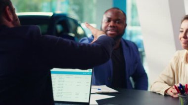 Araba galerisi satıcısı şartları kabul ettikten sonra memnun müşterilerle tokalaşıyor. Ajanlar satış sözleşmesi imzaladıktan sonra müşterilerle tokalaşıyor. Satın alma aracı, kamera A.