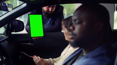 Araba satıcısı, test sürüşünü bitirdikten sonra müşterilerine izole edilmiş ekran tabletinin son fiyatını gösteriyor. Otomobil kataloğunu Chroma Key Cihazı 'ndaki müşterilere gösteren satış temsilcisi, kamera B