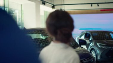 Müşteriler araba galerisine geliyor, güzel mavi modellere bakıyor, ideal yatırım seçeneklerini seçmeye çalışıyorlar. Müşteriler galeriye giriyor, araç satın almak istiyorlar, kamera A.