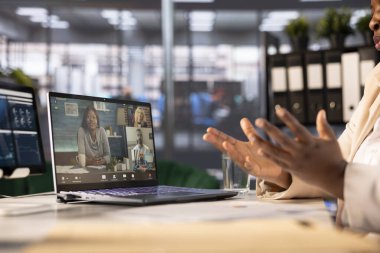 Businesswoman with employees in videocall, using laptop in office. Close up of entrepreneur analyzing financial statistics with partners in videoconference meeting to find strategic insights clipart