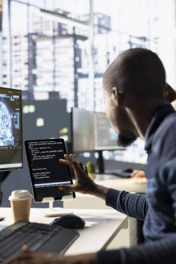 Tablet kullanan programcı, karar verme süreçlerini otomatik hale getirmek için verileri işleyebilen ve analiz edebilen yapay zeka öğrenme modelleri yaratıyor. Cihazı kullanarak yapay zeka programlama yapan bilişim uzmanı