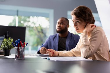Galerideki müşteriler araba satıcısıyla fiyat pazarlığı yapıyor. Afrika kökenli Amerikalı adam ve ortağı, otomobil kiralama için galeri acentasıyla pazarlık ediyor, aracın daha ucuza kiralanmasını umuyor.