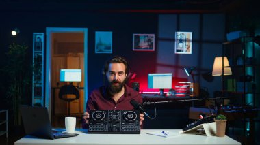 Teknoloji gurusu, DJ denetçisinin yeni çıkan görüntülerini kaydediyor, kutusunu açıyor ve izleyicilere özelliklerini sunuyor. Takipçilere ses karıştırıcı ekipmanı gösterici, Kamera B