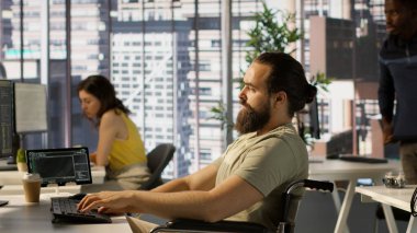 Karar verme süreçlerini otomatikleştirmek için veri işleme ve analizi yapan kişi. Ofiste engelli programlama uzmanı, tekerlekli sandalyede oturuyor, kamera A