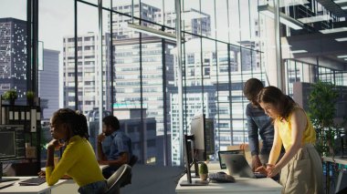 İşçilerle birlikte dizüstü bilgisayara bakıp bitirilmiş projeyi kontrol eden Afrikalı Amerikalı bir yönetici. Şirket yöneticisi ve kadın not defteri, kamera B 'deki verileri analiz ediyorlar.