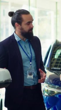 Dikey video araba satış temsilcisi müşterileri araç kapısına ve test kalitesine dokunmaya davet ederek bireylerin yatırım kararı almalarına yardımcı oluyor. Showroom temsilcisi müşterilerden otomobili kontrol etmelerini istiyor