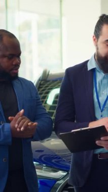 Dikey video galerisi satıcısı müşterilere arabalar, finansman ve alım süreci hakkında sorular soruyor. Araç galerisi temsilcisi müşterilerin garantilerini, hizmetlerini ve mevcut ekstra özelliklerini açıklıyor