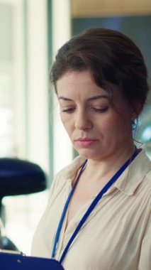 Araba galerisi satıcısının dikey video portresi müşterilerin potansiyel otomobil seçeneklerini değerlendirmesine yardımcı oluyor. Araç özelliklerini ve fiyatlandırma seçeneklerini açıklamak için tutulan neşeli satıcı kadın