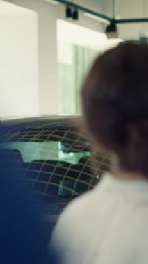 Dikey video müşterileri araba galerisine geliyor, güzel mavi modellere bakıyor ve ideal yatırım seçeneklerini seçmeye çalışıyorlar. Müşteriler galeriye giriyor, araç satın almak istiyorlar, kamera var.