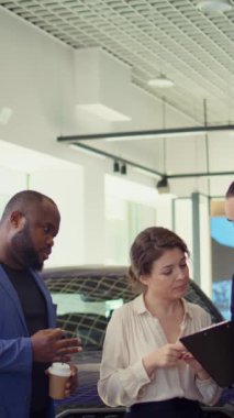 Dikey video araba galerisi satıcısı test sürüşünden sonra memnun müşteriler için satış sözleşmesi imzalıyor. Showroom temsilcisi müşterilere satın almak için ekstra özellikler öneriyor, imza istiyor