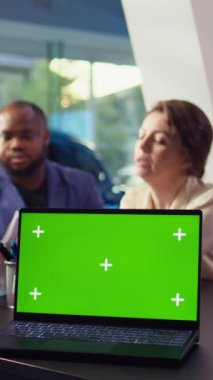 Dikey video satış elemanı müşteriler için araba test sürüşünü planlamak için yeşil ekran dizüstü bilgisayarındaki randevu listesine bakıyor. Showroom temsilcisi deneme sürüşünü maket kullanarak düzenliyor