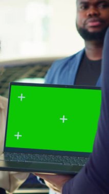 Dikey video satış elemanı çift için izole edilmiş ekran dizüstü bilgisayarda araba modelleri gösteriyor, tavsiyelerde bulunuyor. Showroom temsilcisi, modelleme defteri ve kamera üzerinden müşterilere finansman seçenekleri sunar