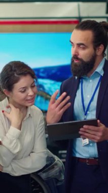 Dikey video araba galerisi satıcısının müşterilere tablet üzerinden ürün sunumu yapması ve uygun tavsiyelerde bulunması. Showroom temsilcisi, A kamerasındaki müşterilere finansman seçenekleri sunar.
