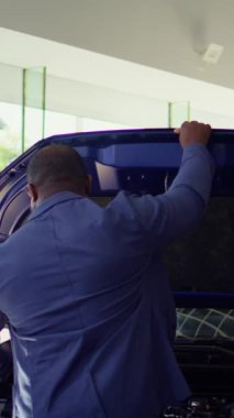 Araba galerisindeki dikey video müşterileri araç kaputu altındaki bileşenlere bakıyor, test sürüşüne çıkmadan önce özelliklerini ve özelliklerini kontrol ediyorlar. Araç modellerini karşılaştıran, kullanılan parçaları gören istemciler