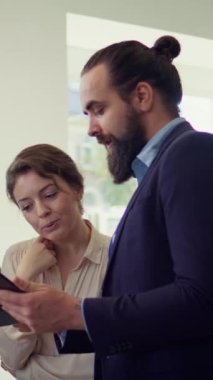 Dikey video araba galerisi satıcısının müşterilere tablet üzerinden ürün sunumu yapması ve uygun tavsiyelerde bulunması. Showroom temsilcisi, aygıt, kamera B 'deki müşterilere finansman seçenekleri sunar