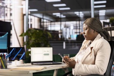 Muhasebeci, iş rakamlarını ve belgelerin doğruluğunu kontrol etmek için cep telefonu kullanıyor. Çalışan arkadaşlarıyla mesajlaşmak için bilgisayarlı şirket bilgi kayıtlarını incelemeye ara veriyor.