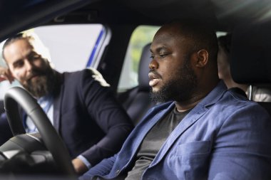 Satış temsilcisi, test sürüşü sırasında aracın markasını, modelini, kilometre oranını ve özelliklerini açıkladı. Showroom çalışanı, müşterilerin otomobili değerlendirmelerine yardımcı olur.