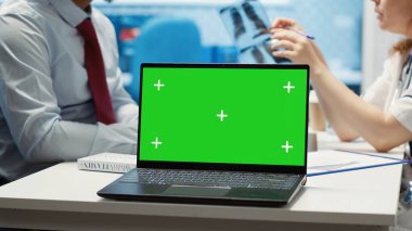 Doktor, muayene sırasında sağlık hizmeti teşhisi konan izole edilmiş bir ekranın yanındaki hastayla test sonuçlarını tartışıyor. Doktor tedavi planını ve tavsiyeyi tartışıyor. Kamera A.