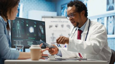 Tıbbi uzman teşhis için röntgen görüntülemesini açıklıyor, muayene sırasında tarama yorumu yapıyor. Profesyonel doktor bayan müşteriye geri bildirim yapar. Kamera A.